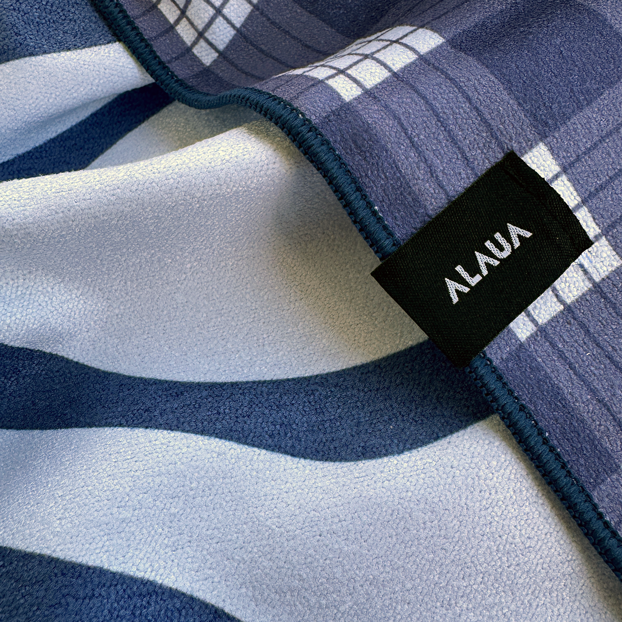 Close-up of the ulu hawaiian quilt palaka towel with blue and white patterns and an ALAUA label.